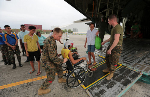 Soldados estadounidenses suben a una persona en silla de ruedas a un avión 