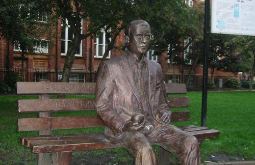 estatua de bronce en un parque, La figura de Touring sentada en un banco