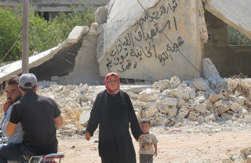 Una mujer con un niño delante de unos escombros