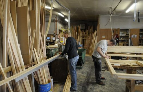 Un joven y otra persona no tan joven trabajan en una carpintería