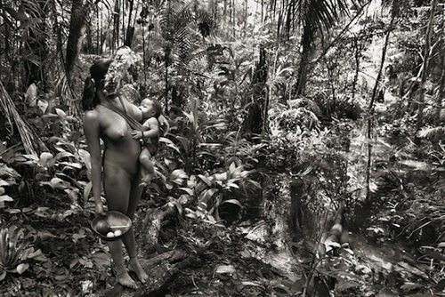 Una mujer en la selva con un bebé en brazos que mama