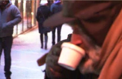 Un mendigo bebe un café en la calle
