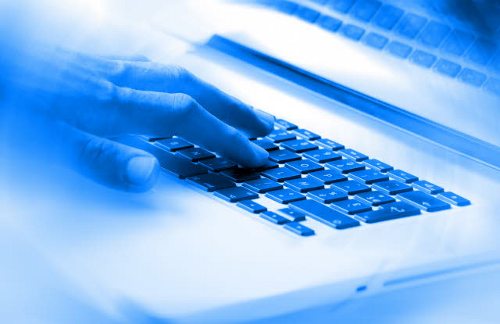 Una mano sobre el teclado de un ordenador en una atmósfera azul