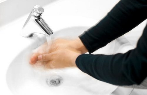 Una mujer se lava las manos bajo el grifo