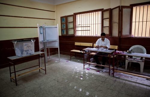 Un colegio electoral completmente vacío, solo la persona que recibe las papeletas