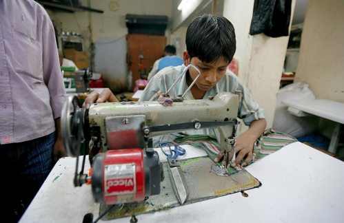 Un niño cose a máquina en una fábrica 