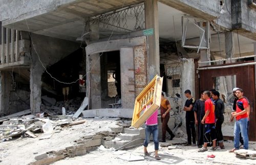 Jóvenes palestinos ante un edificio completamente derruído