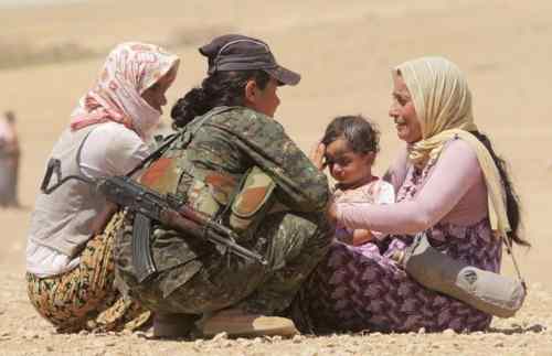 Dos mujeres con un bebé hablan con otra con uniforme militar