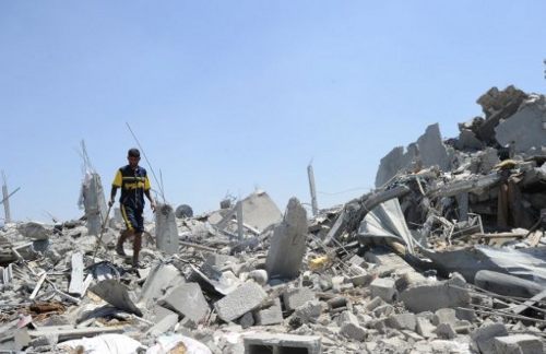 Un hombre anda sobre los restos de un edificio completamente destruido