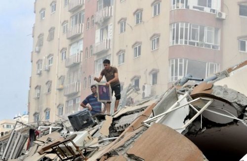 Dos hombres sobre escombros de un edificio en Gaza