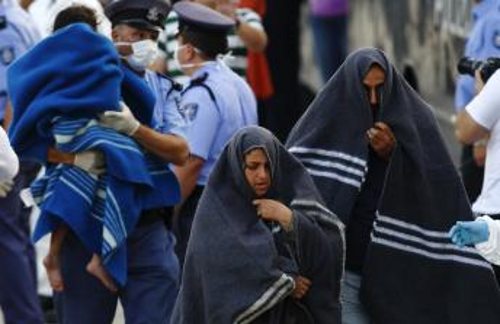 Inmigrantes envueltos con mantas, policía que lleva a un menor