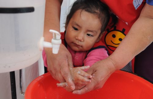 Una voluntaria lava las manos de una niña
