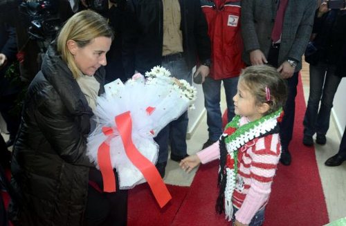 Federica Mogherini, recibe un ramo de flores que le entrega una niña