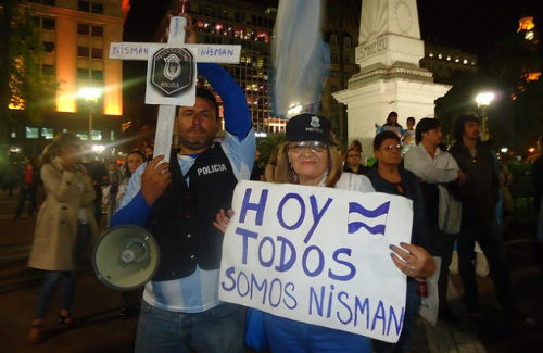 Manifestantes, un hmbre y una mujer llevan una pancarta y una cruz en las que se leen 
