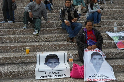 Metonia Carrillo sentada en una escalera con una pancarta con la foto de su hijo en el regazo