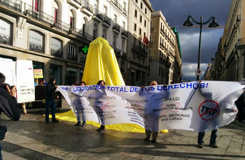 El oso y el madroño de la Puerta del Sol de Madrid tapados, delante ecologistas con una pancarta