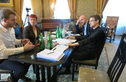 Los Parlamentarios suecos y Edward Snowden sentados alrededor de una mesa hablando en un lugar elegante