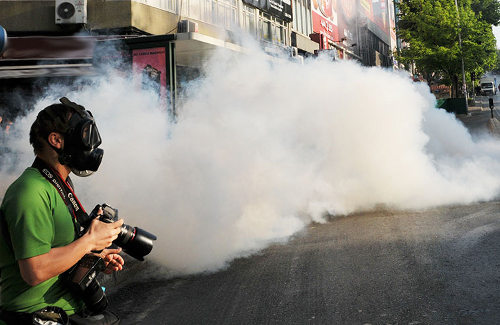 Una nube de gas al lado de un fotógrafo con una máscara antigas en la cara