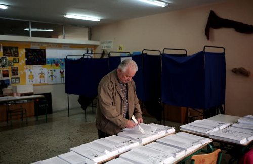 Un hombre mira atentamente las papeletas en un colegio electoral