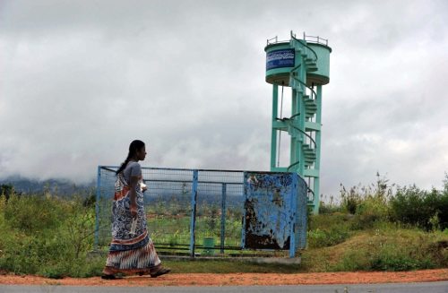 Una mujer pasa al lado de un depósito de agua que parece abandonado
