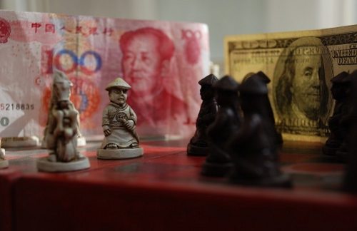 Un tablero de ajedrez con un billete de dólar y otro chino de fondo