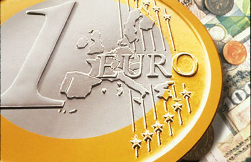 Una moneda de euro sobre billetes nacionales