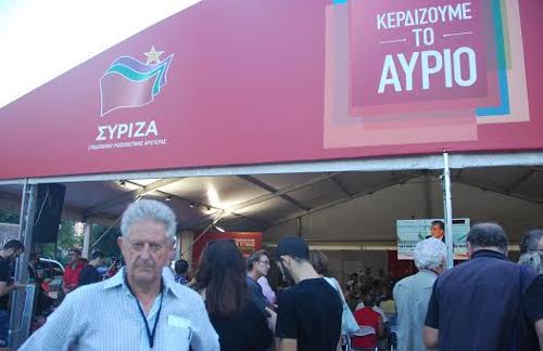 Griegos pasando junto a un cártel de Syriza