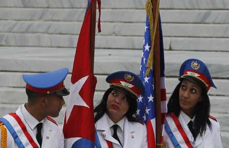 Dos chicas con sendas banderas de Cuba y EE . UU y un chico